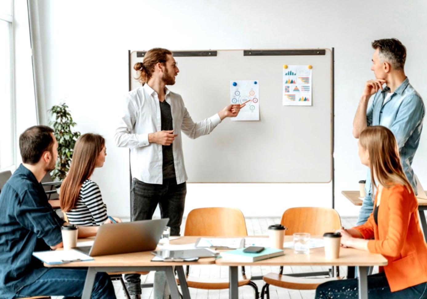Small group financial workshop with instructor explaining concepts at whiteboard